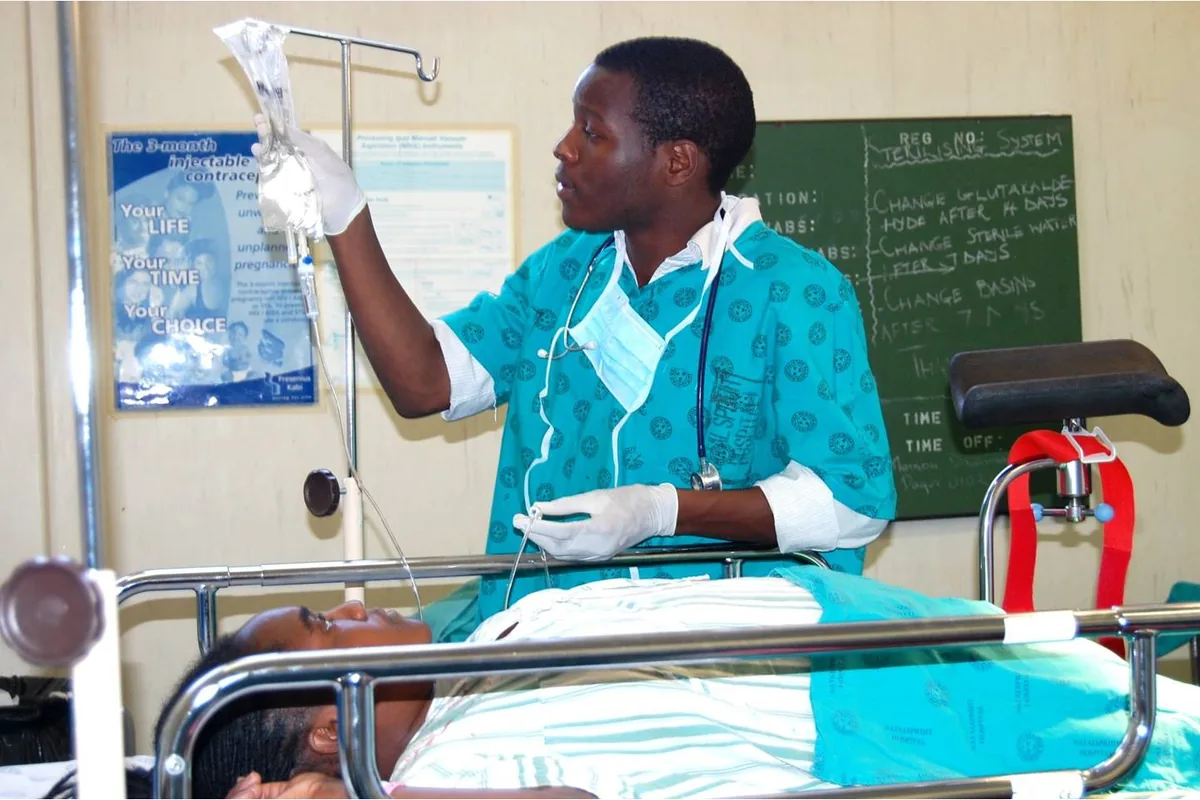A young doctor adjusting a drip beside a patient's bed