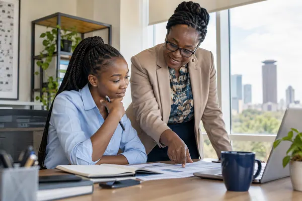 A supervisor reviewing work with a young intern in an office