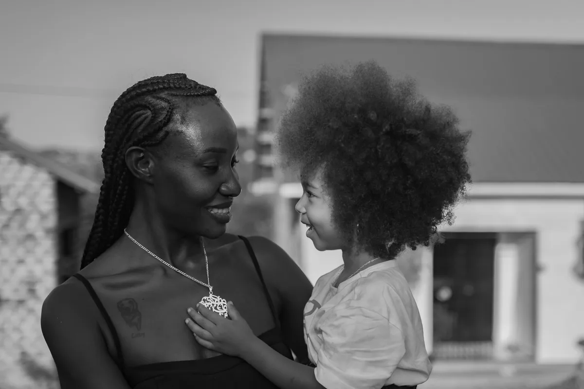 A smiling mother holding her young child, in black and white