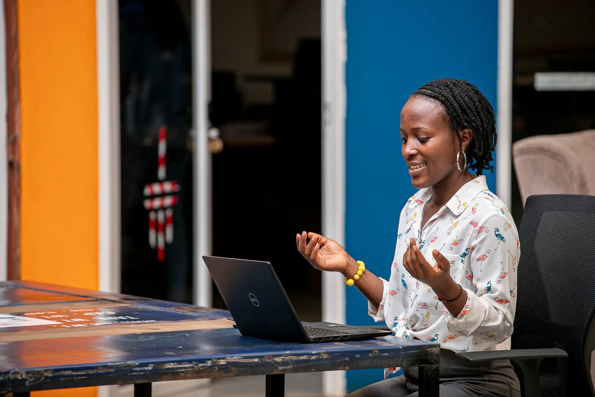 A young woman in Kampala talking and gesturing during a video call on her laptop